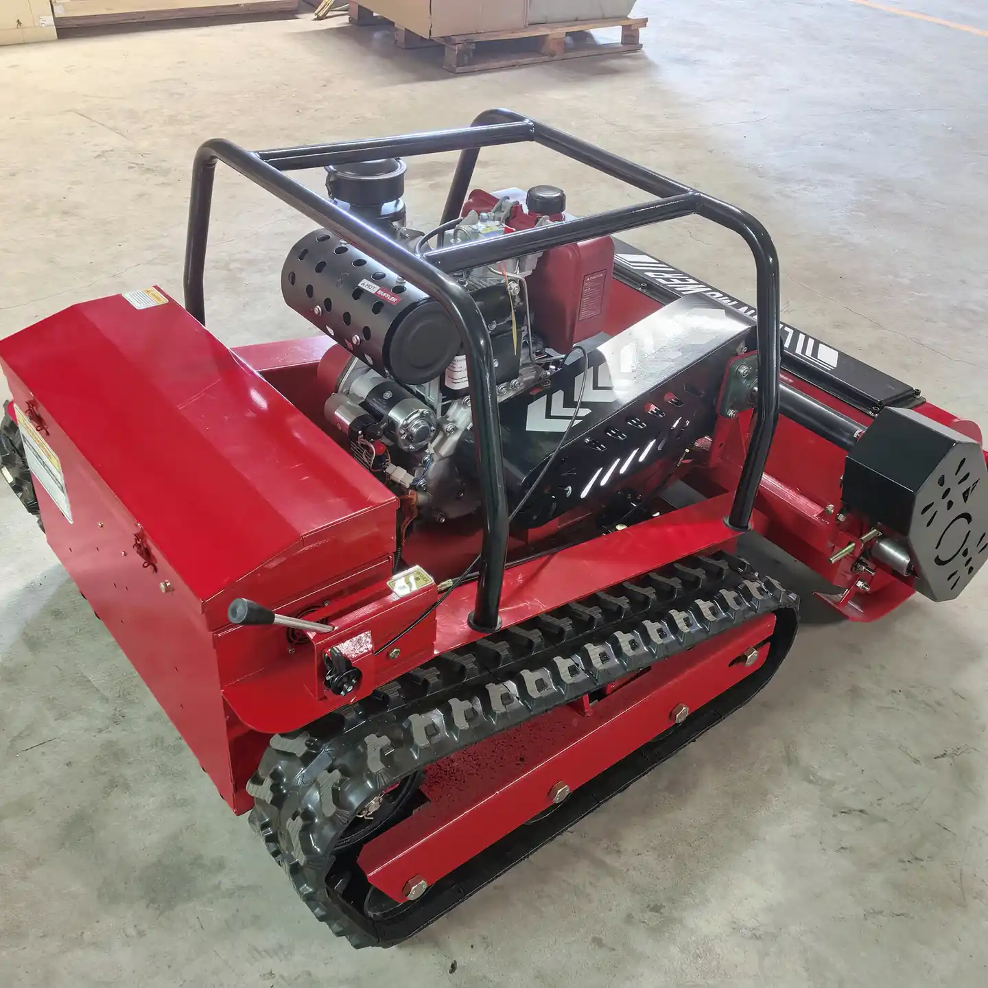 Front view of a tracked remote control mower on a factory floor