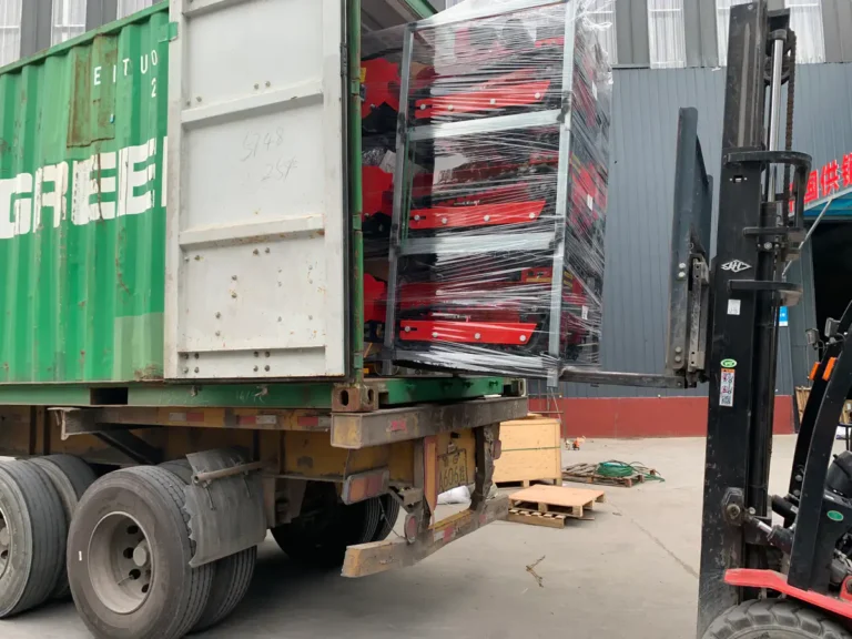 Forklift loading packed MERI remote mowers into an export container