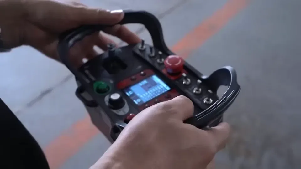 Hands checking the display and controls on a remote mower transmitter