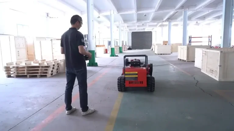 Operator guiding a tracked remote mower during a factory-floor control demonstration