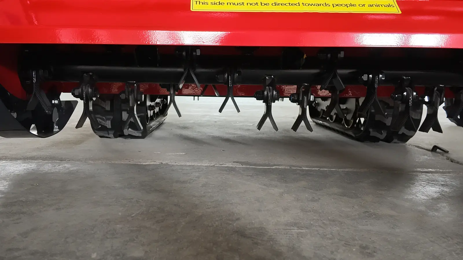 Remote mower flail rotor shown below its guard and warning label