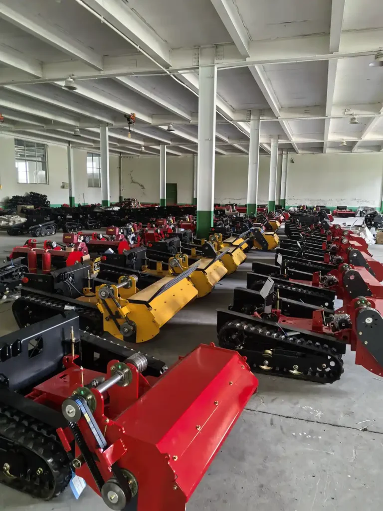 Tracked mower chassis and flail deck assemblies at different factory build stages