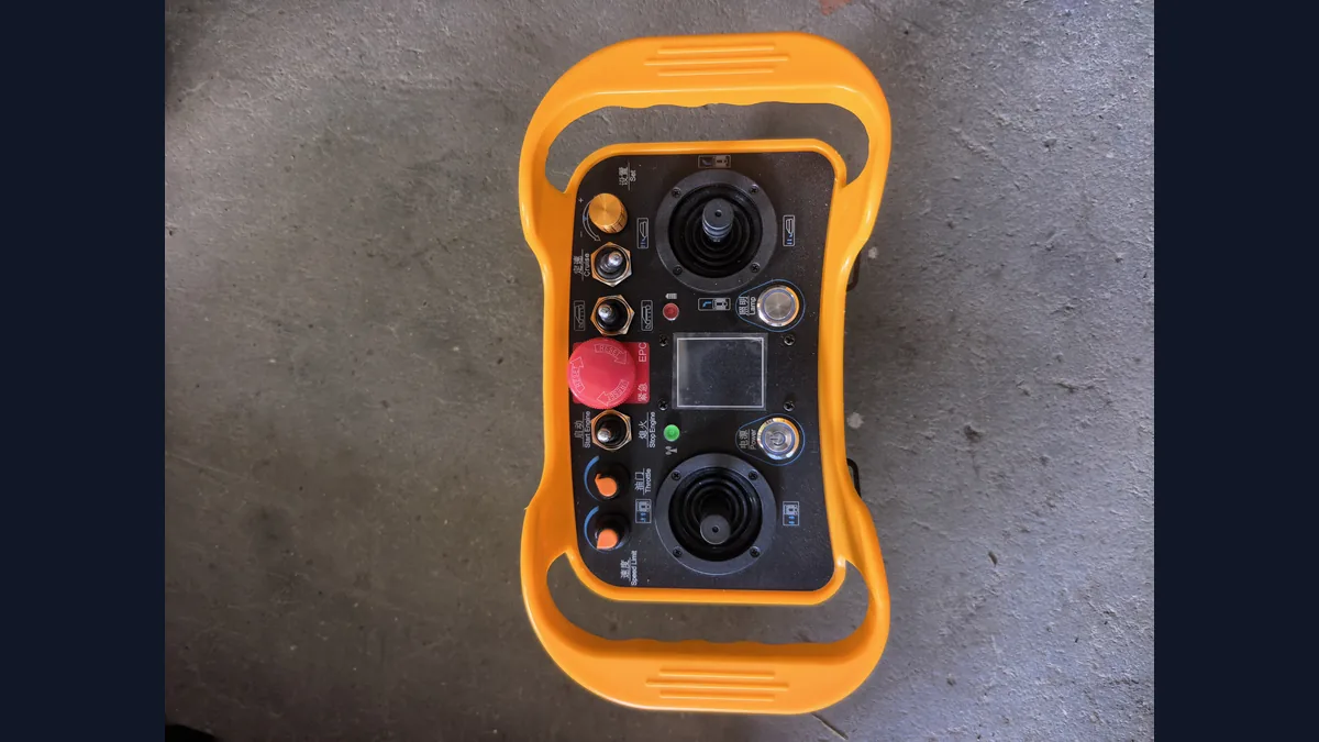 Orange industrial remote controller photographed on a workshop floor